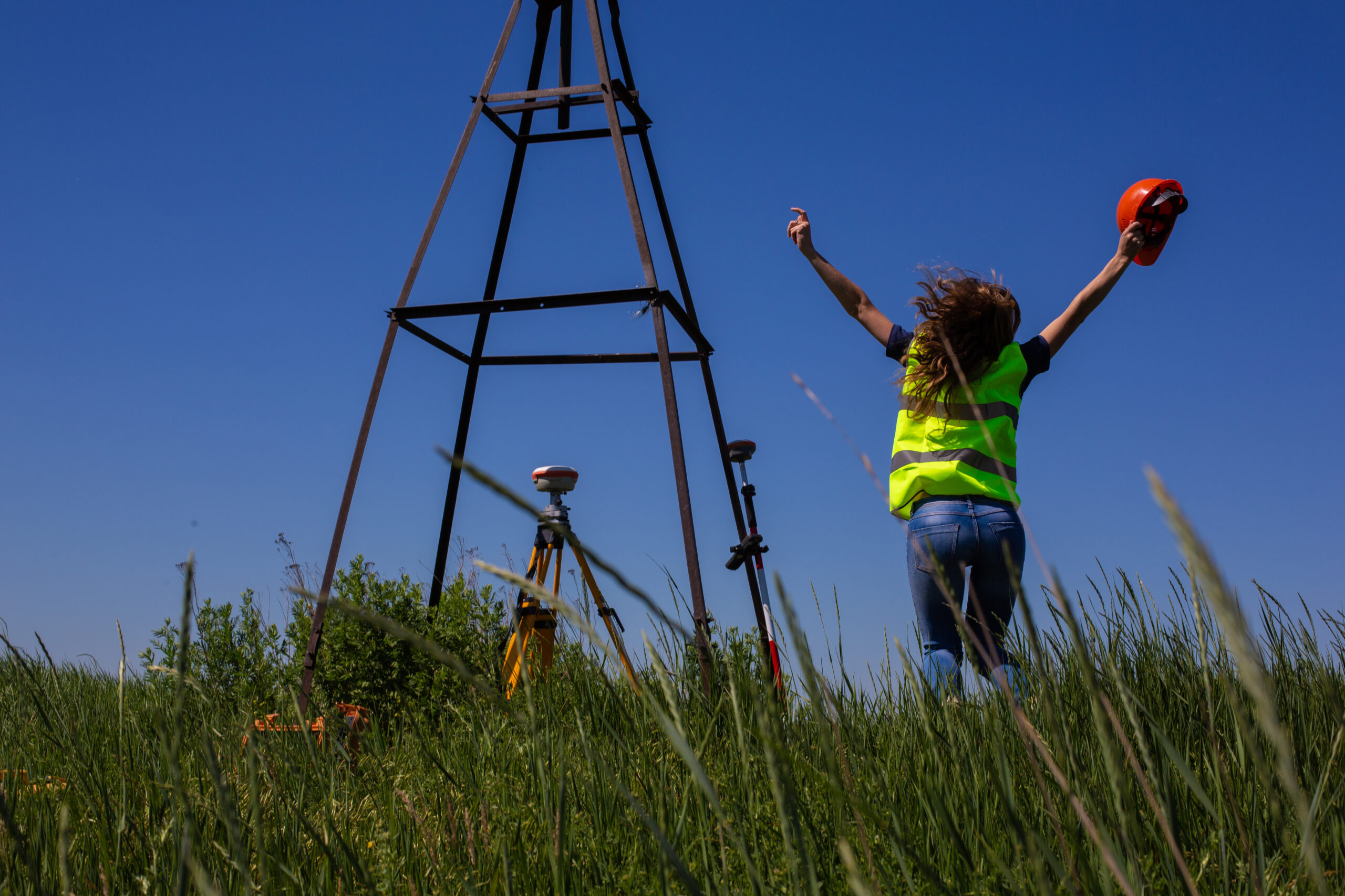 professional female land surveyor measures ground control point using a gps rover. green field on a background. happy woman finish the work.